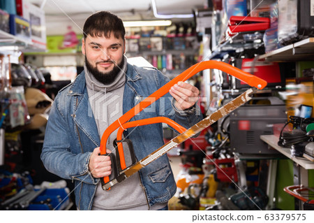 Portrait adult male with hacksaw in tools store Portrait adult male with hacksaw in tools store 63379575