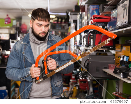 Man choosing hacksaw in tool store 63379697