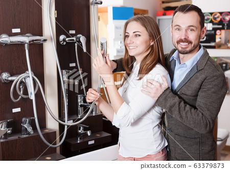 Happy young couple looking for modern functional shower mixer Happy young couple looking for modern functional shower mixer 63379873