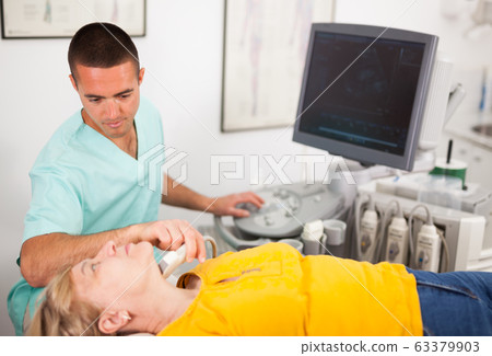 Man sonographer examining female patient Man sonographer examining female patient 63379903