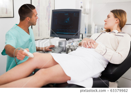 Man sonographer examining female patient Man sonographer examining female patient 63379982