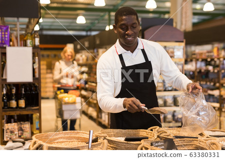 Man working in bulk food department of supermarket Man working in bulk food department of supermarket 63380331