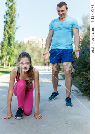 Girl standing in start position for run Girl standing in start position for run 63380571