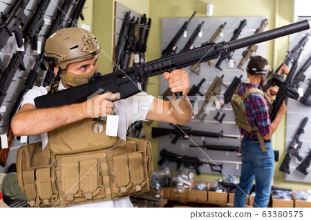Male customers try on ammunition with weapon Male customers try on ammunition with weapon 63380575
