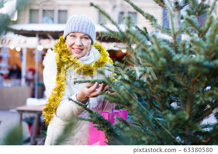 Woman is preparing for Christmas and choosing X-mas tree 63380580