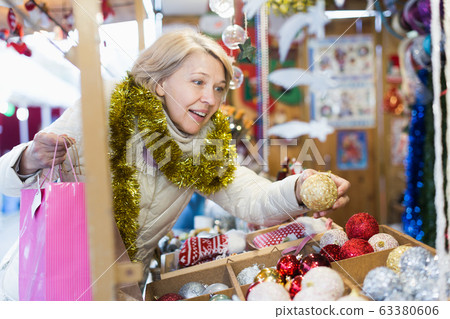 Smiling woman choosing Christmas toys at Christmas market Smiling woman choosing Christmas toys at Christmas market 63380606