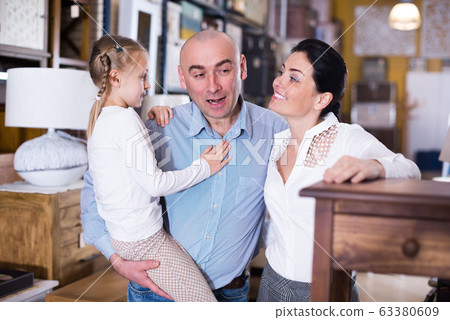 Family couple with small girlare choosing nightstand Family couple with small girlare choosing nightstand 63380609
