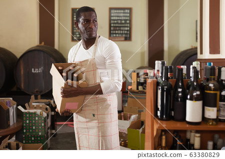 man worker posing with cardboard box with wine man worker posing with cardboard box with wine 63380829