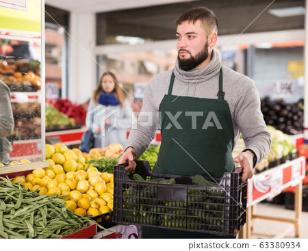 Positive seller in apron working in vegetables market Positive seller in apron working in vegetables market 63380934
