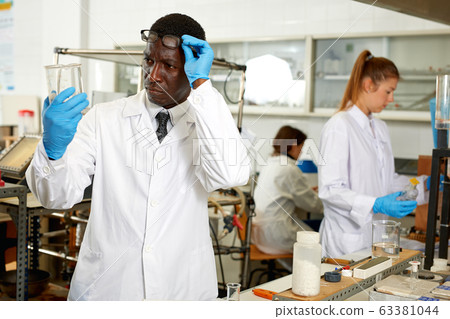 Focused lab technician checking for result of experiment in laboratory 63381044