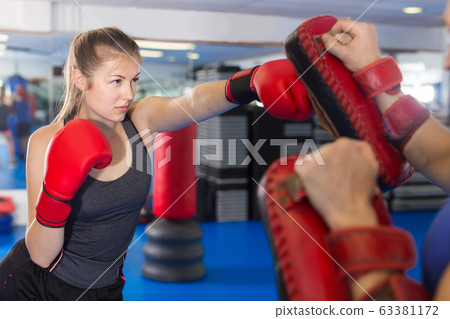 man is training with woman and punching gloves in box gym. 63381172