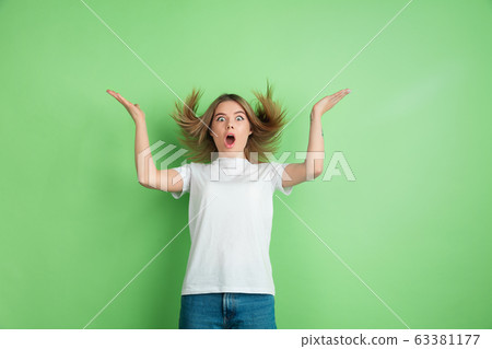 Caucasian young woman's portrait on green studio background Caucasian young woman's portrait on green studio background 63381177