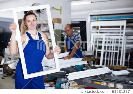 Young happy female worker with plastic window frame Young happy female worker with plastic window frame 63381227