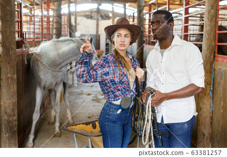 Girl and man having emotional discussion at stable 63381257
