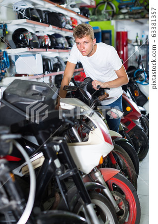 Portrait of male motorcyclist looking on the bike in the store Portrait of male motorcyclist looking on the bike in the store 63381357
