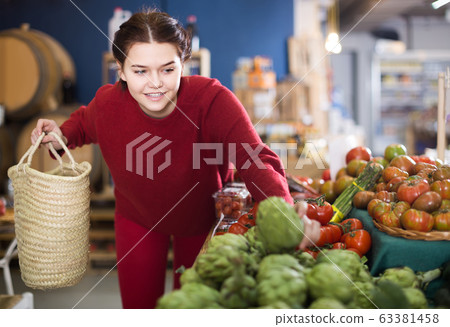 woman choosing artichokes in farm food store woman choosing artichokes in farm food store 63381458