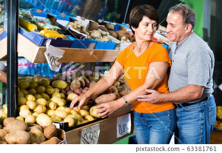 Smiling couple is choosing potato in the supermarket. Smiling couple is choosing potato in the supermarket. 63381761