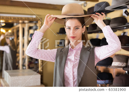 Woman trying on hat during shopping Woman trying on hat during shopping 63381900