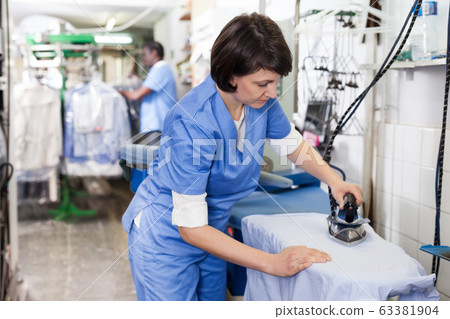 Girl ironing in laundry Girl ironing in laundry 63381904