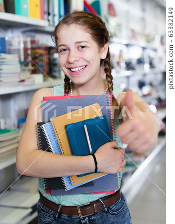 Happy teen girl with colored copybooks 63382149