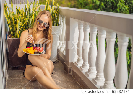 Young woman resting on a balcony with a plate of fruit. life-work balance, relaxation healthy Young woman resting on a balcony with a plate of fruit. life-work balance, relaxation healthy 63382185