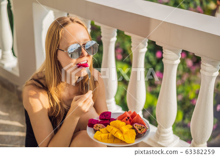 Young woman resting on a balcony with a plate of fruit. life-work balance, relaxation healthy Young woman resting on a balcony with a plate of fruit. life-work balance, relaxation healthy 63382259
