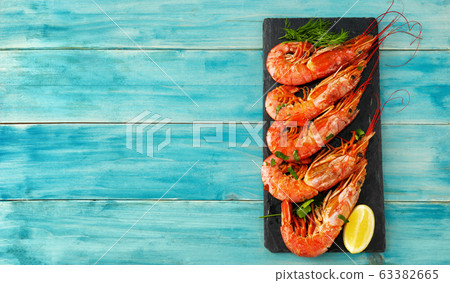Top view of red huge prawns on a slate plate and blue background Top view of red huge prawns on a slate plate and blue background 63382665