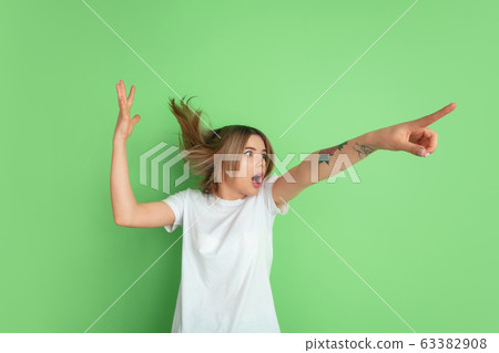 Caucasian young woman's portrait on green studio background Caucasian young woman's portrait on green studio background 63382908