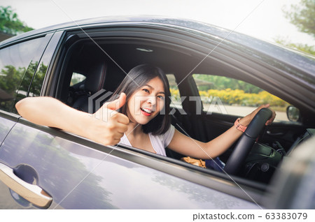 woman driving her new car and showing thumb up woman driving her new car and showing thumb up 63383079