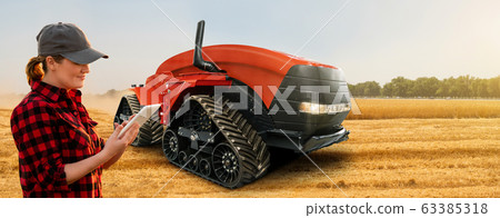 Farmer with digital tablet controls autonomous tractor on a smart farm Farmer with digital tablet controls autonomous tractor on a smart farm 63385318