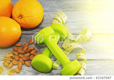 Lots of oranges, dumbbells, measuring tape on a 63387097