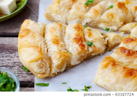 Traditional feta cheese phyllo pastry pie, banitsa. Wooden background. Close up. Traditional feta cheese phyllo pastry pie, banitsa. Wooden background. Close up. 63387724