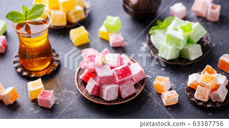 Assortment of Turkish delights with glass of tea. Grey background. Assortment of Turkish delights with glass of tea. Grey background. 63387756