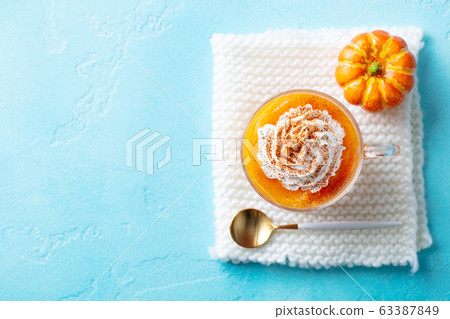Pumpkin latte in glass cup. Blue background. Copy space. Top view. Pumpkin latte in glass cup. Blue background. Copy space. Top view. 63387849