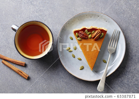 Pumpkin pie on a plate with cup of tea. Grey background. Close up. Top view. Pumpkin pie on a plate with cup of tea. Grey background. Close up. Top view. 63387871