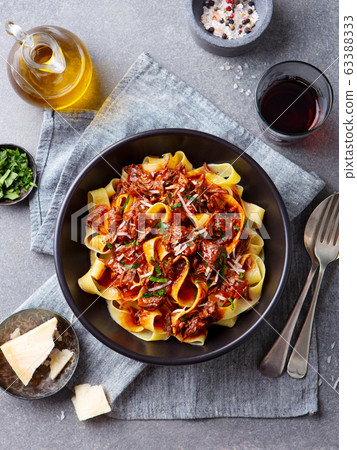 Pasta pappardelle with beef ragout sauce in black bowl. Grey background. Top view. 63388333