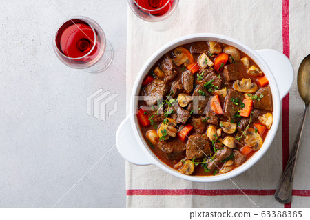 Beef bourguignon stew with vegetables and red wine. Grey background. Top view. Beef bourguignon stew with vegetables and red wine. Grey background. Top view. 63388385