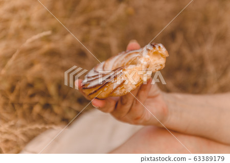 Woman's hand holds cake on a blurred background. 63389179