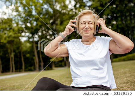 Senior sports woman enjoying music outdoors Senior sports woman enjoying music outdoors 63389180