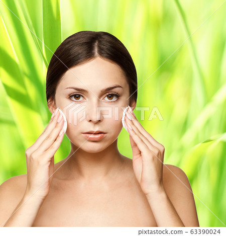 Young brunette girl with botton pads near face. 63390024