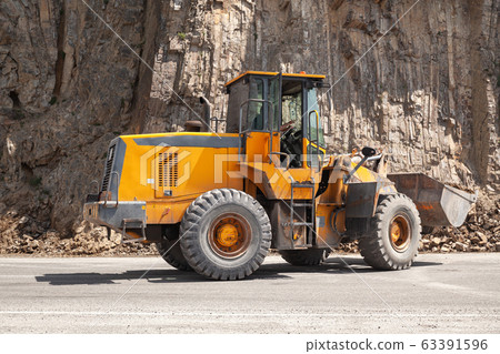 Heavy yellow tractor clears a mountain road Heavy yellow tractor clears a mountain road 63391596