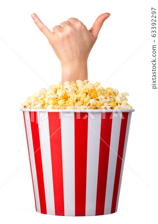 Female hand sticks out of a bucket with popcorn isolated on white background Female hand sticks out of a bucket with popcorn isolated on white background 63392297