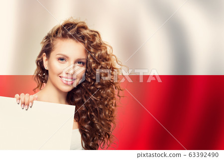 Cute young woman showing white paper on the Poland 63392490