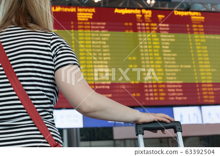Woman looks at the scoreboard at the airport. 63392504