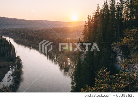 Scenic landscape, man on on edge of cliff meeting beutiful sunrise over mountain river Usva, Russia, Ural mountains Scenic landscape, man on on edge of cliff meeting beutiful sunrise over mountain river Usva, Russia, Ural mountains 63392623