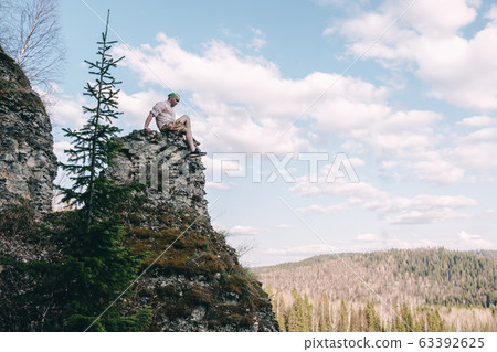 Young hiker looking down from a top of a mountain Young hiker looking down from a top of a mountain 63392625