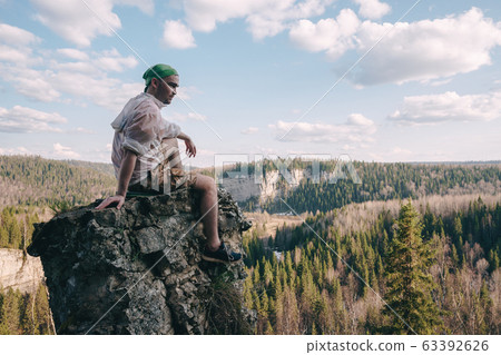 Young hiker looking down from a top of a mountain Young hiker looking down from a top of a mountain 63392626