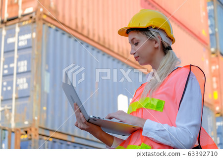 Portrait of beautiful technician use laptop in front of cargo containers with day light Portrait of beautiful technician use laptop in front of cargo containers with day light 63392710