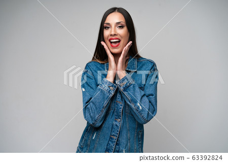Beautiful caucasian girl in a denim jacket posing in the studio on a white background. Beautiful caucasian girl in a denim jacket posing in the studio on a white background. 63392824