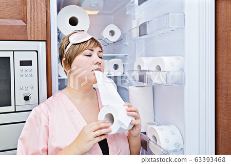 Woman in pajamas greedily eats toilet paper near Woman in pajamas greedily eats toilet paper near 63393468